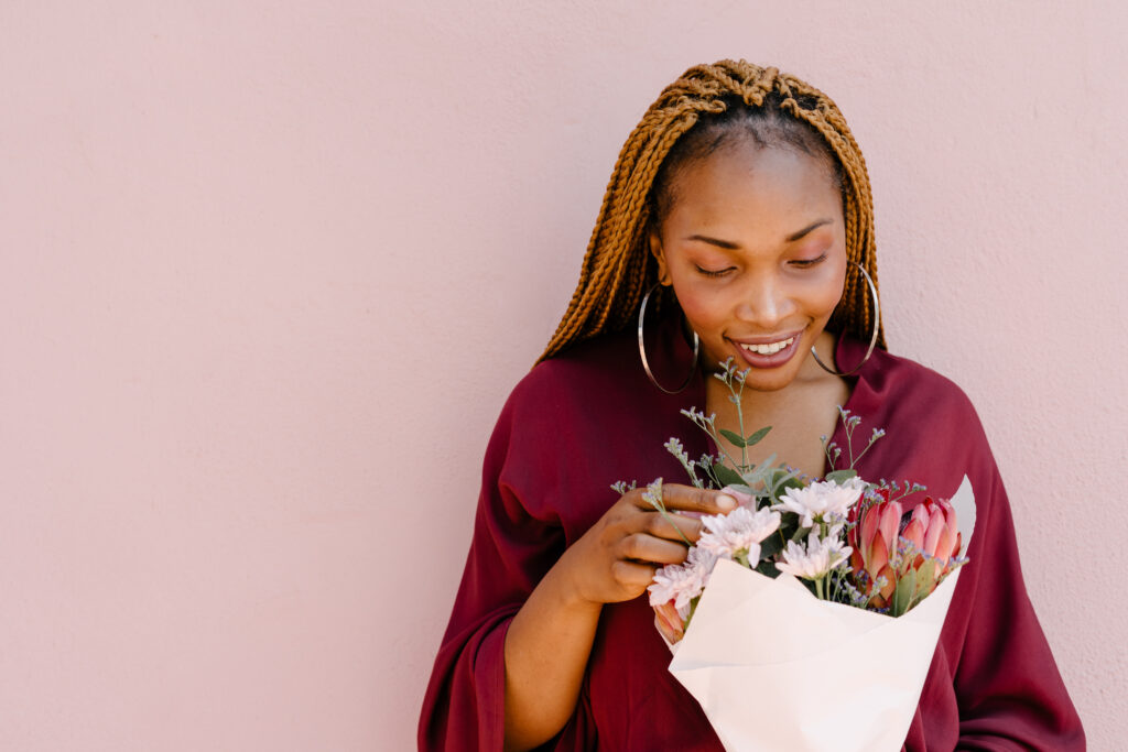 Woman in a maroon dress holding a protea bouquet.